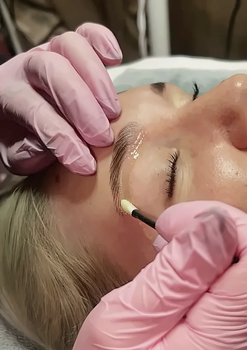 Brow waxing at Just Face It: pink gloved hands applying wax to a client's brow