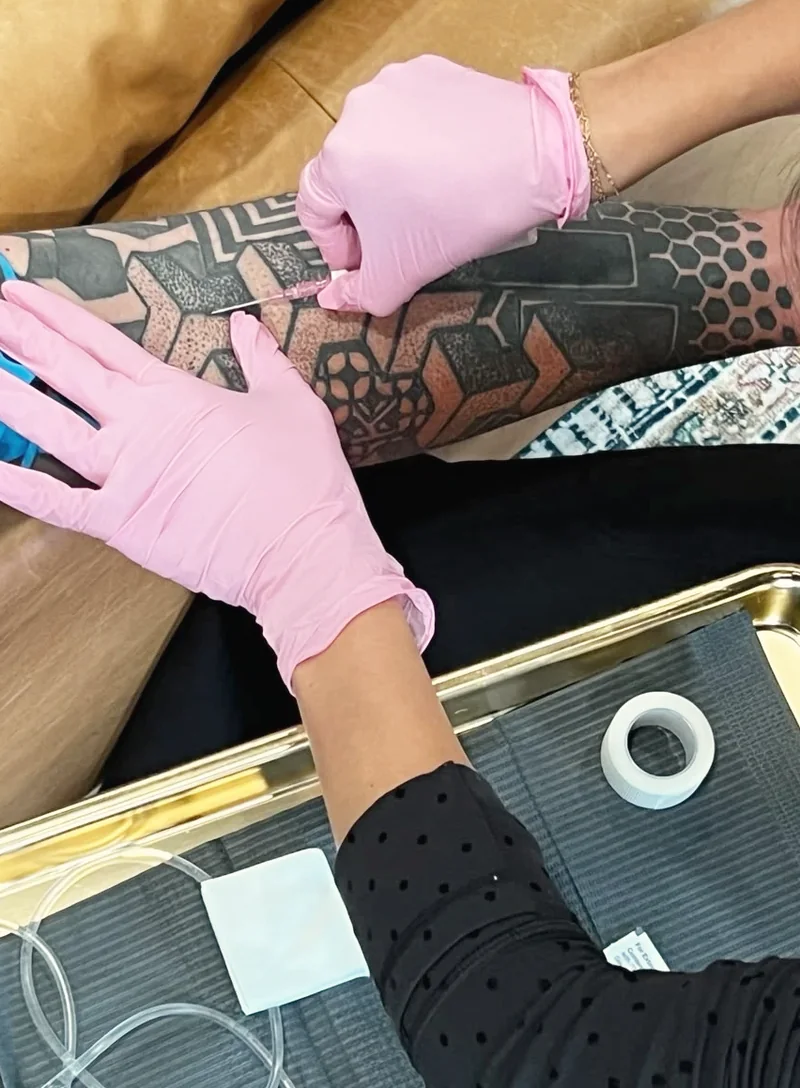 IV therapy at Just Face It: a nurse in pink gloves placing an IV