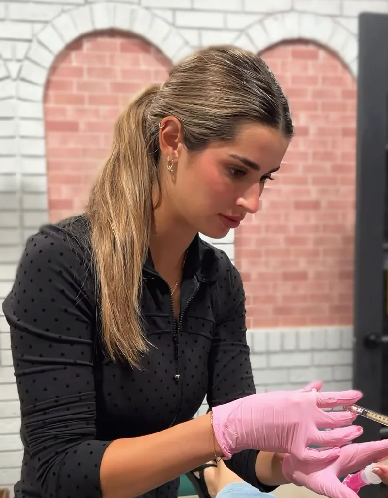 One of our nurses in pink gloves placing Derma PRP, in the room with the pink brick arches