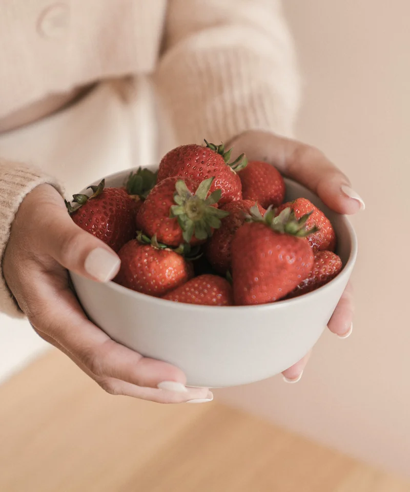 Hands holding a bowl of fresh strawberries